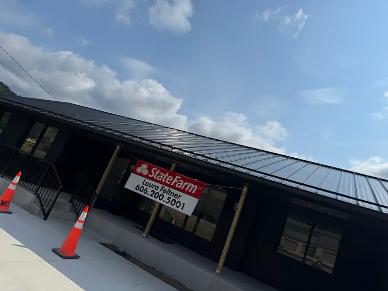 State Farm insurance office with a new black standing-seam metal roof, a State Farm banner over the entrance and traffic cones out front