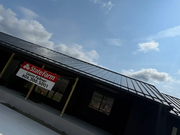 Lower-angle view of the State Farm office black standing-seam metal roofline against a blue sky