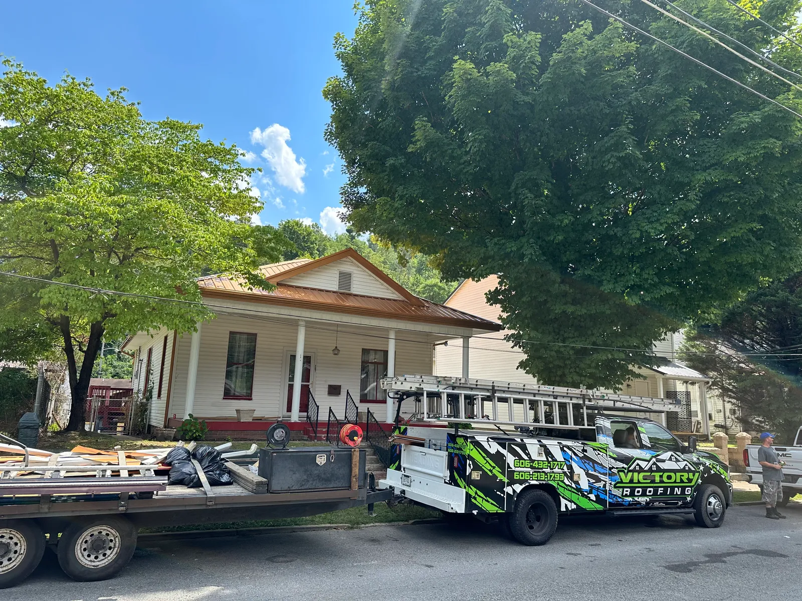 Victory Metal crew on-site in Pikeville, KY — branded Victory Roofing truck in front of a home with a new clay standing-seam metal roof