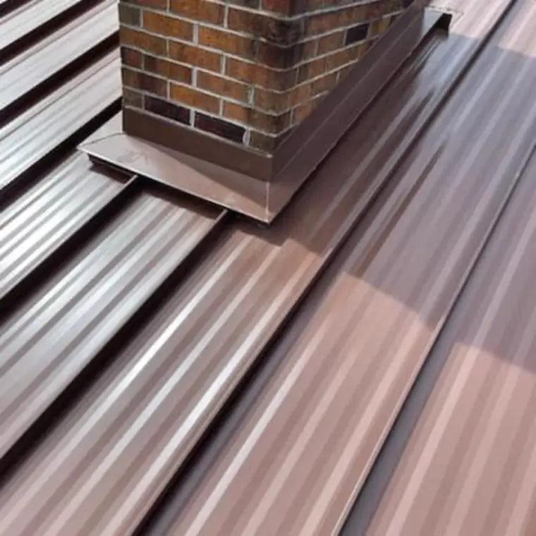 Close-up of brown standing-seam panels and watertight brown flashing at the base of a brick chimney