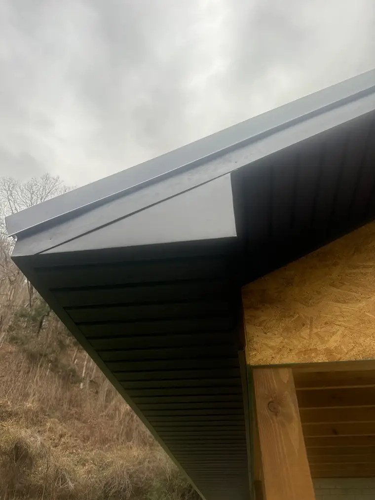Angled view of finished black metal fascia and soffit trim wrapping a gable corner of a home