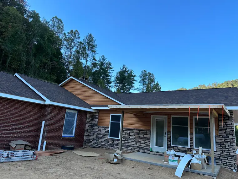 Another angle of the cedar-tone sided home with stacked-stone veneer, brick, and a shingle roof